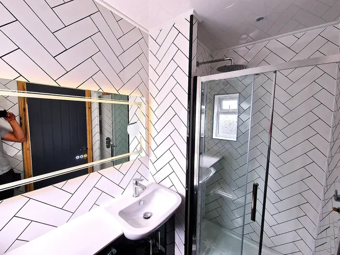 Bathroom with white herringbone tiles and an illuminated mirror