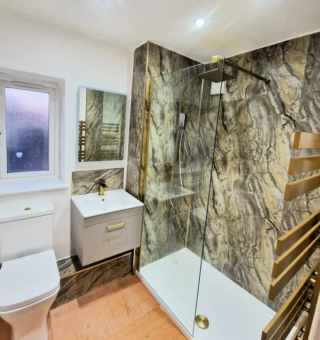 Bathroom with stone-effect wall panels and brushed gold shower