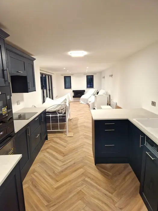 Inside the extension, a navy kitchen and herringbone floor running through to the living area