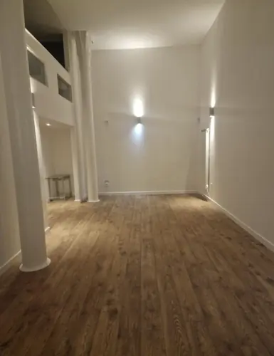 Open-plan living area in the rental flat with a white column and wood-effect floor
