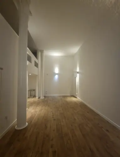 Open-plan living area with wall lights and a high ceiling