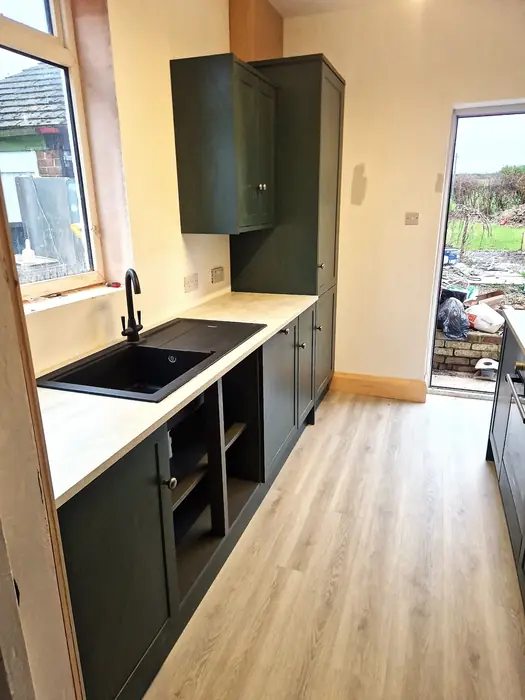 Galley kitchen with dark units and a garden door