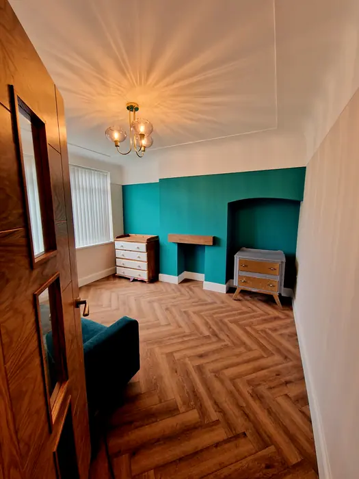 Room with herringbone flooring and a teal feature wall