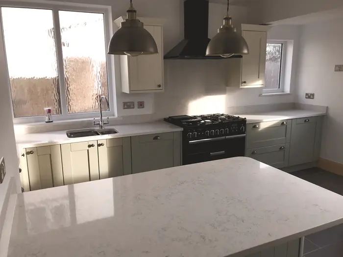 Kitchen with sage units, range cooker and a quartz island