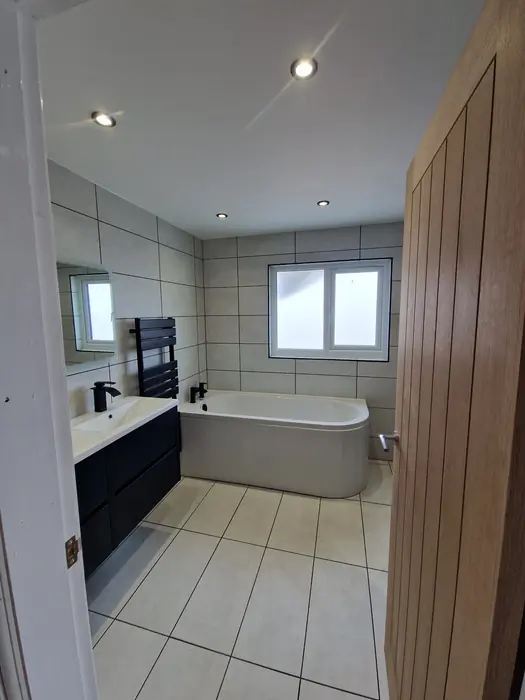 Loft bathroom with a freestanding bath and oak door