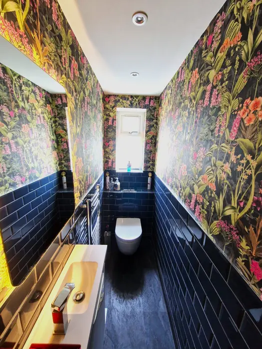 Downstairs bathroom with floral wallpaper and dark tiles